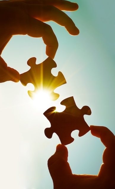 two hands of businessman to connect couple puzzle piece with sky background.Jigsaw alone wooden puzzle against sun rays.one part of whole.symbol of association and connection.business strategy